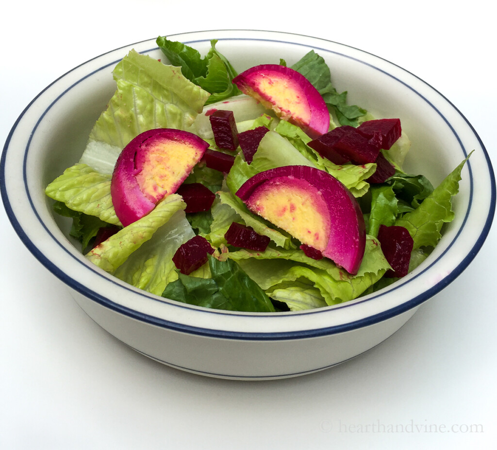 Salad bowl with lettuce, diced pickled red beets and pickled eggs sliced.