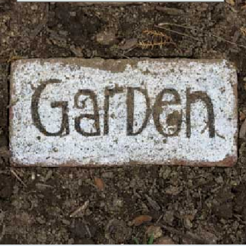 Painted white brick with the word garden in black