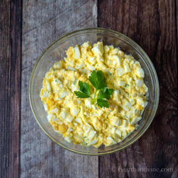 Egg salad in a bowl with flat leaf parsley decoration in the middle