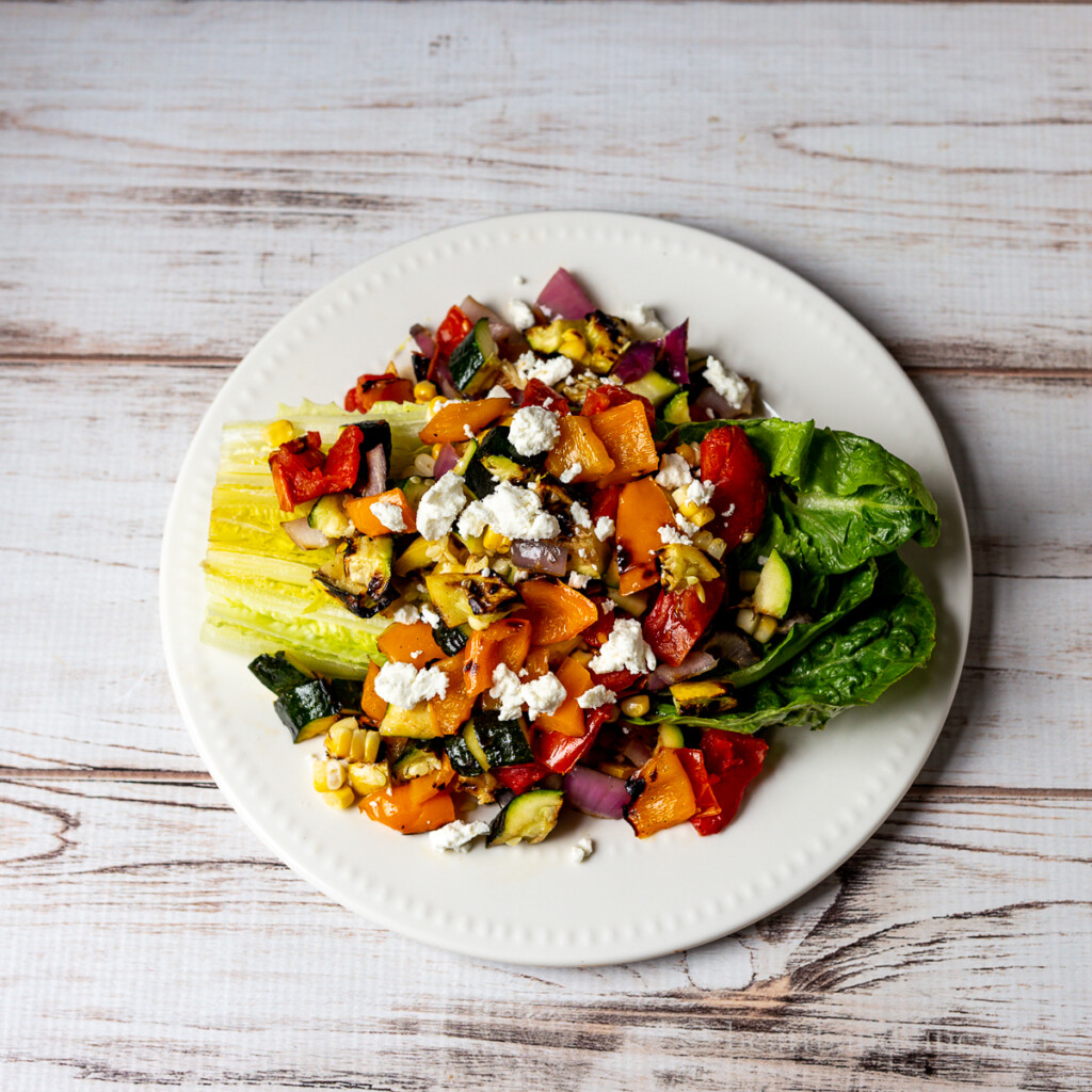 Grilled vegetable salad with goat cheese on a wedge of romaine lettuce.