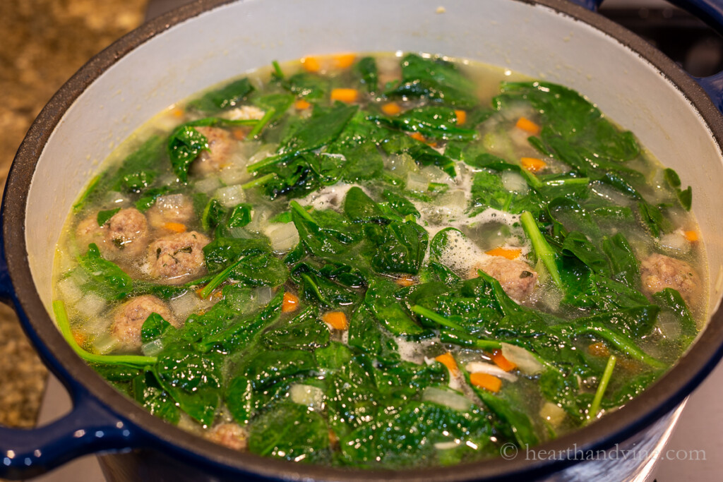 Large pot of Italian wedding soup simmering on the stove.