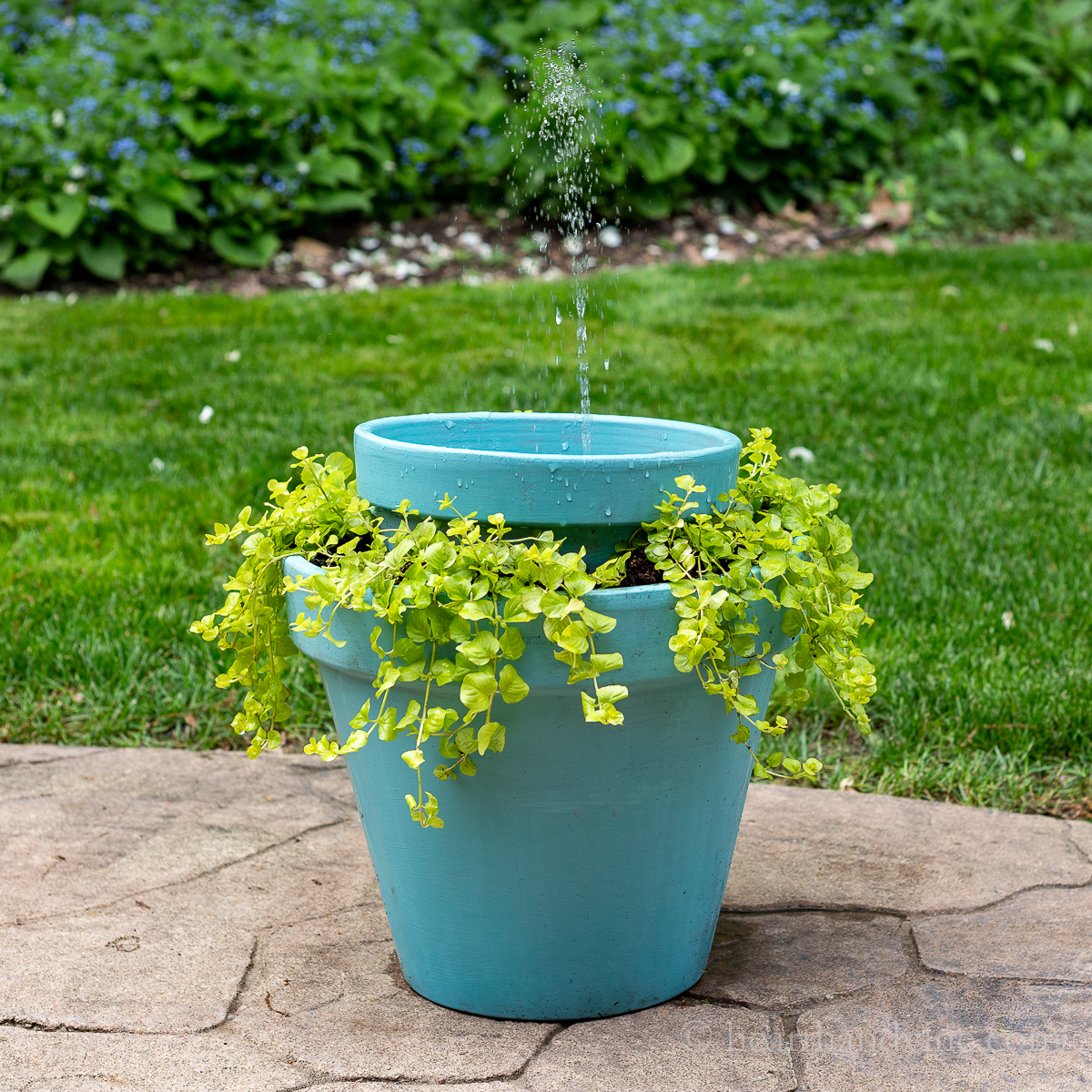 Double clay pots nested with greener planted in bottom and a solar fountain on top.