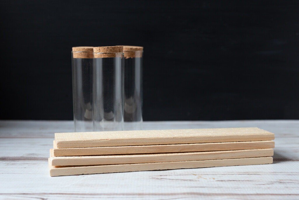 Glass jars with cork tops and pieces of wood stacked together.