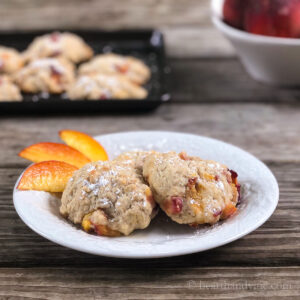Two peach fritters on a place with peach slices