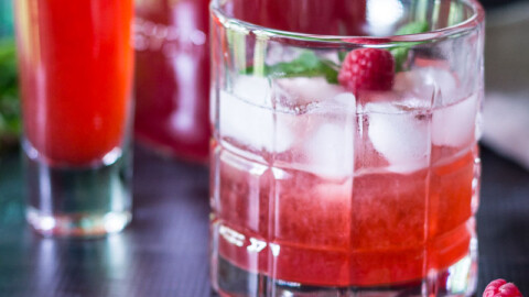 Glass with a raspberry shrub cocktail, a fresh berry and mint