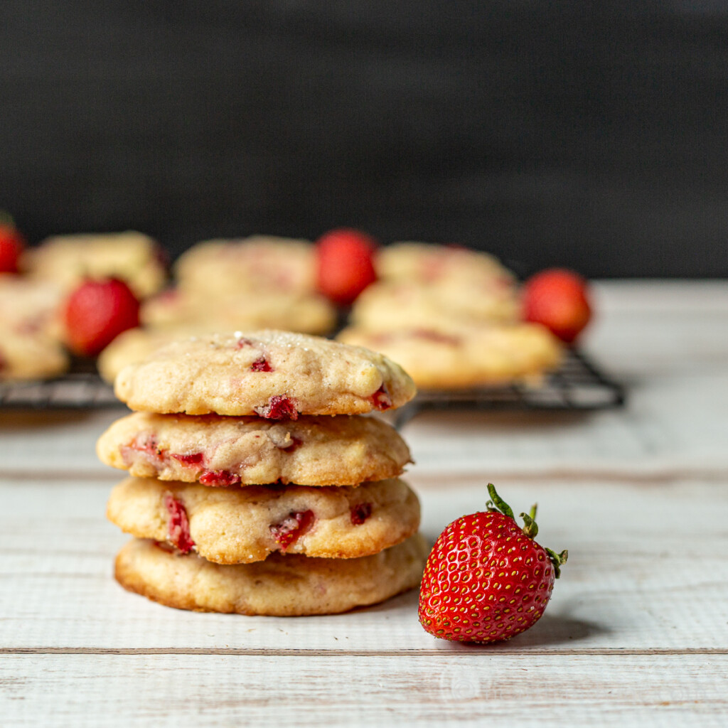 Stacked strawberry cookies with fresh strawberries.