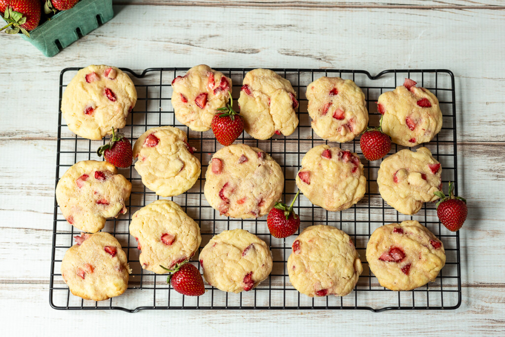 Strawberry cookies on a cooling rack with fresh berries.