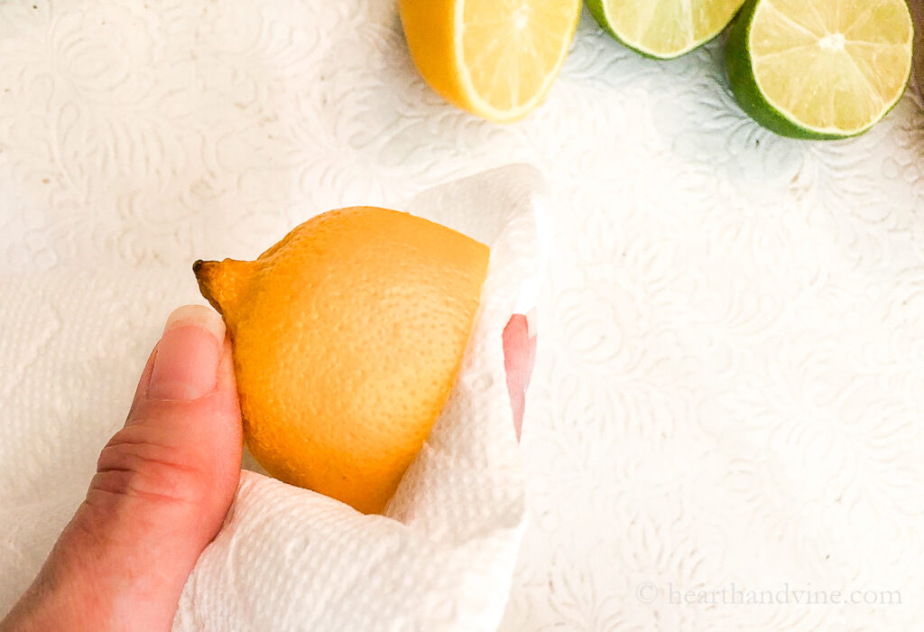 Half a lemon with a paper towel blotting off the juice on the cut side.