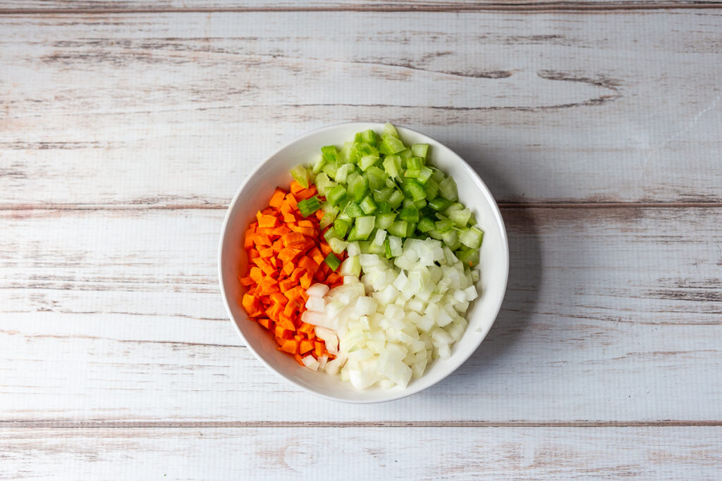 Bowl of chopped up carrots, onions and celery.