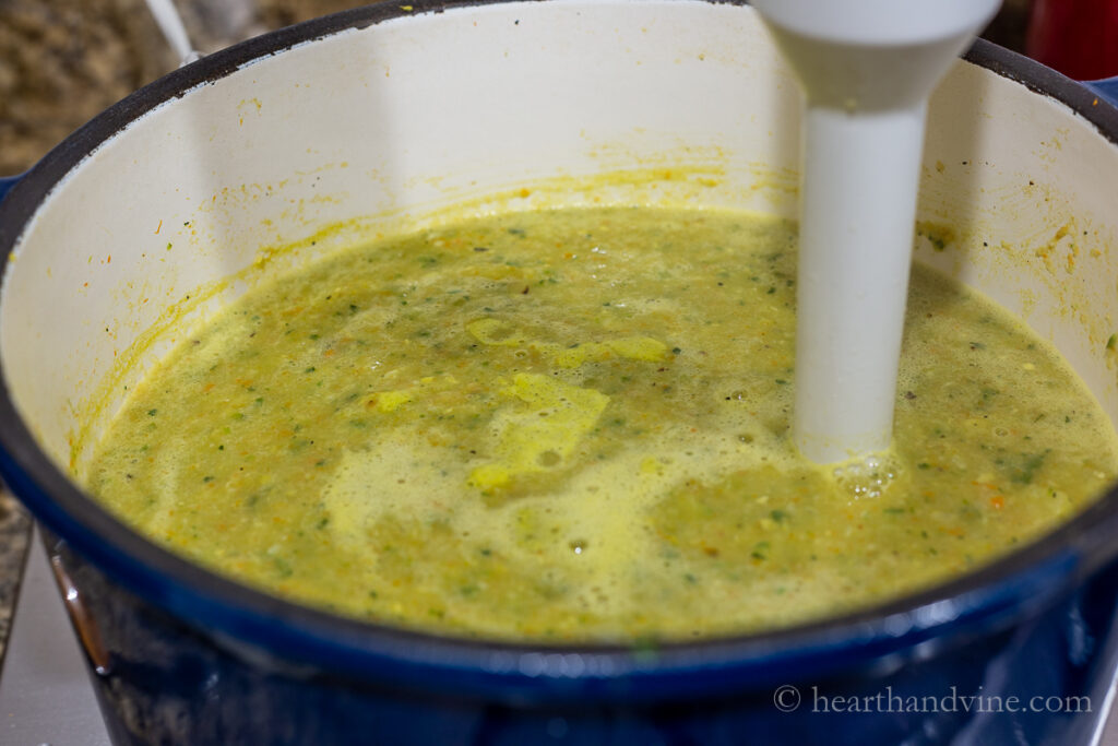 Immersion blender pureeing zucchini and corn on the stove.