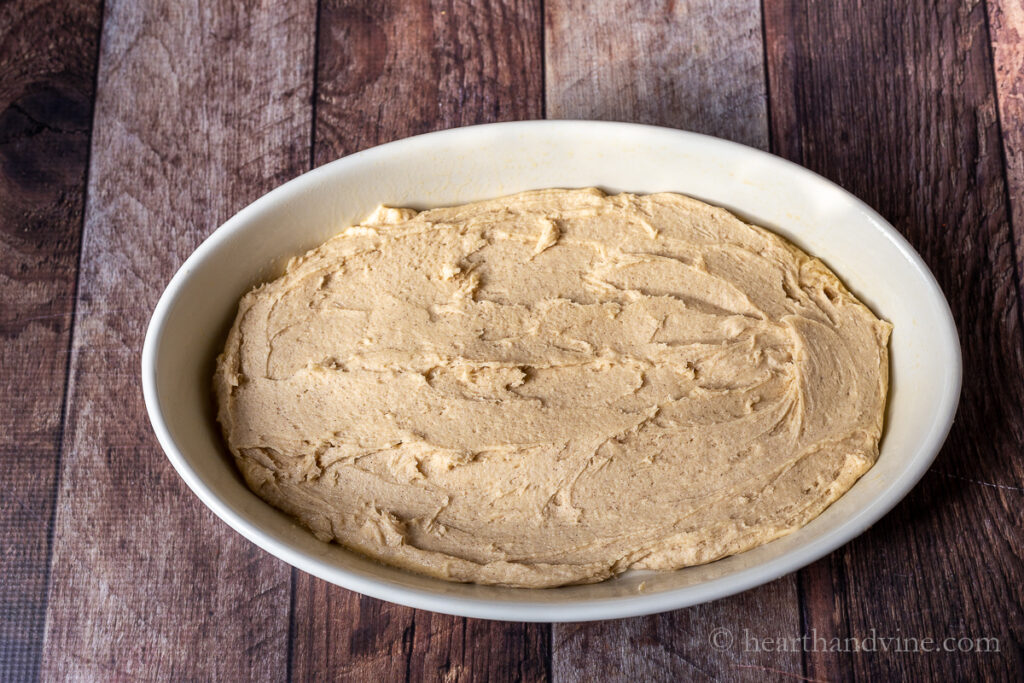 Cake batter spread into an oval baking pan.