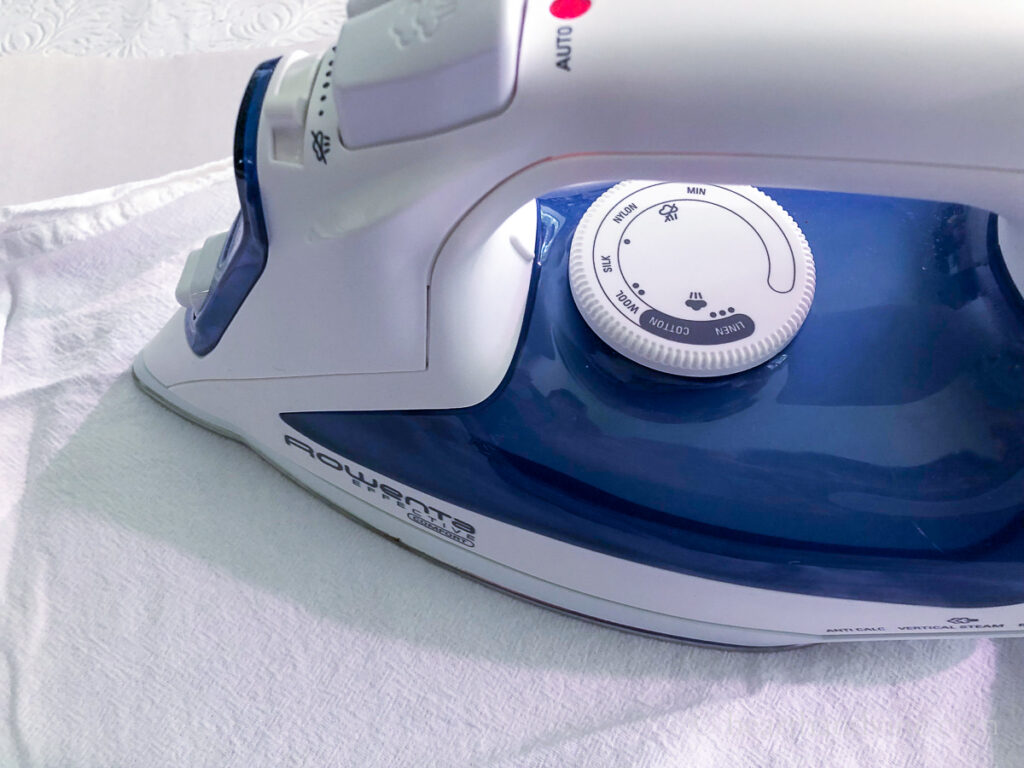 Iron pressing a white tea towel.