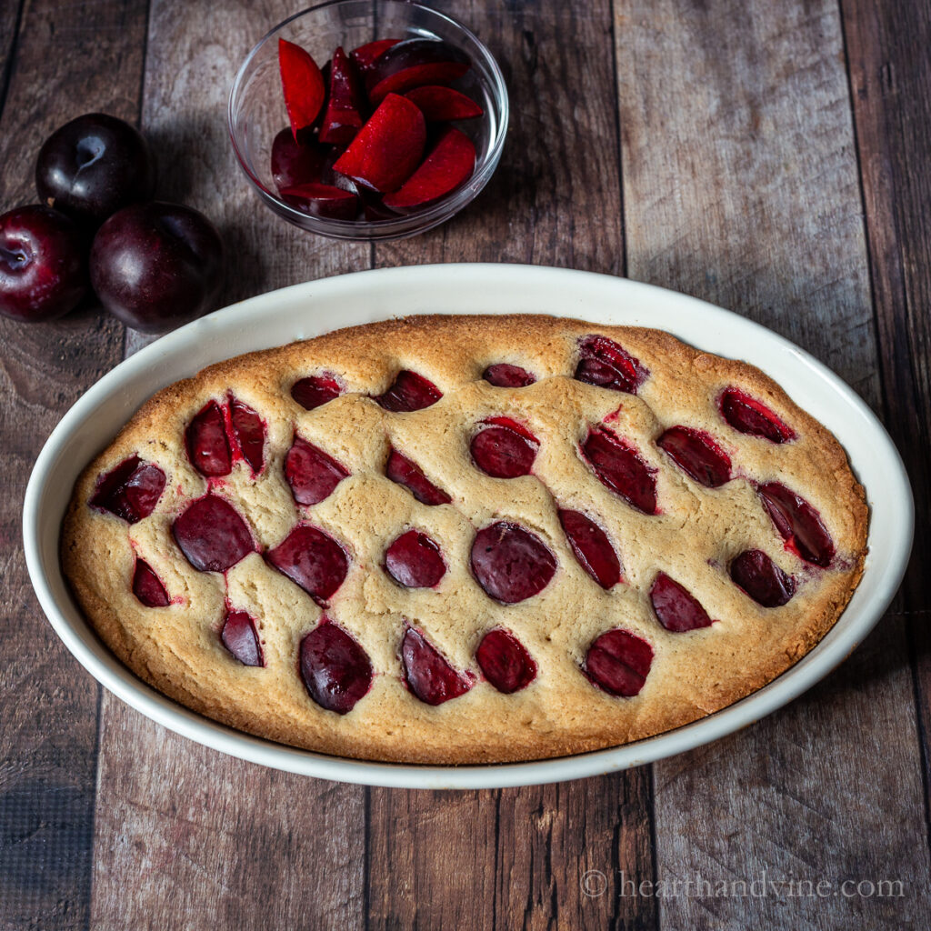 Fresh baked plum cake in a large oval baking pan.