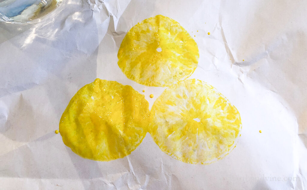 Three stamps lemons with yellow paint on paper showing the image after each print.