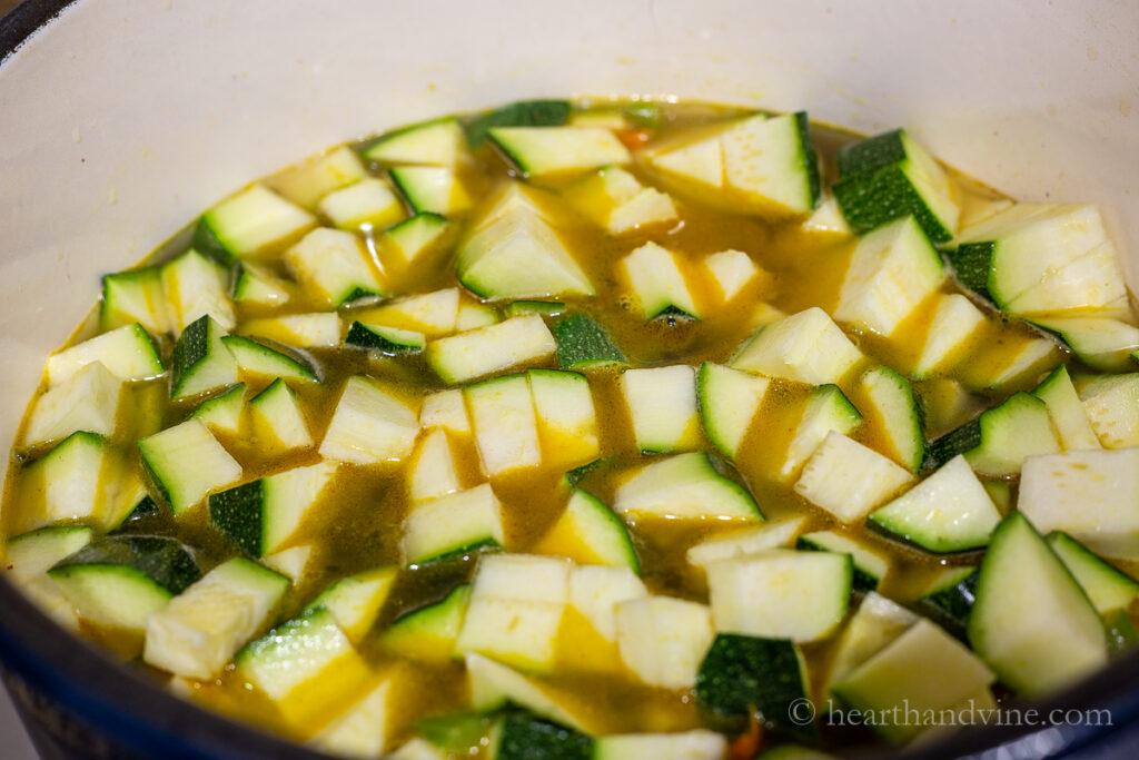 Sauce pot with chopped zucchini and broth.