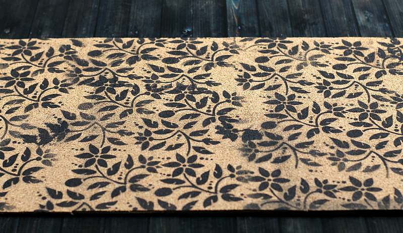 Stenciled cork with floral print in black paint.