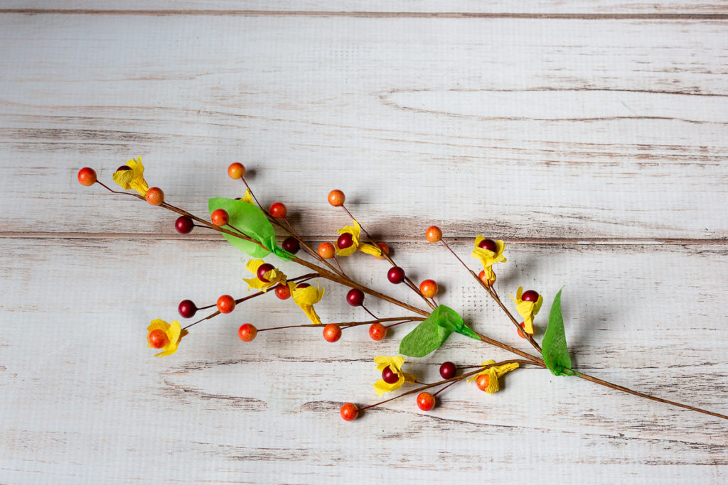 Berry stem turned into bittersweet look with yellow paper around the berries and green leaves.