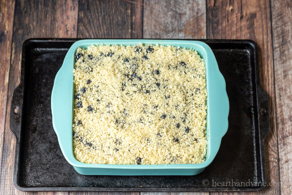 Blueberry brown Betty assembled in a square baking pan on a cookie sheet.