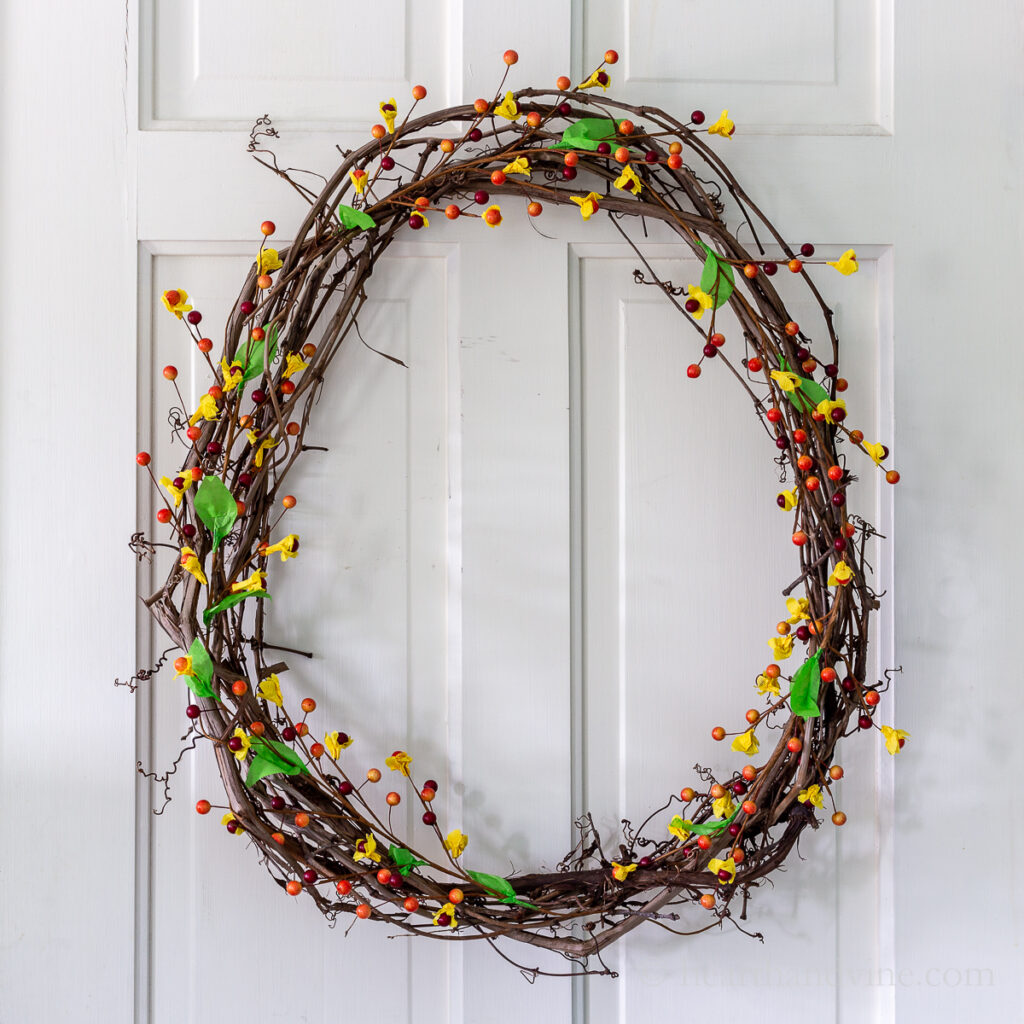 Grapevine wreath with artificial bittersweet looking berries on a white door.