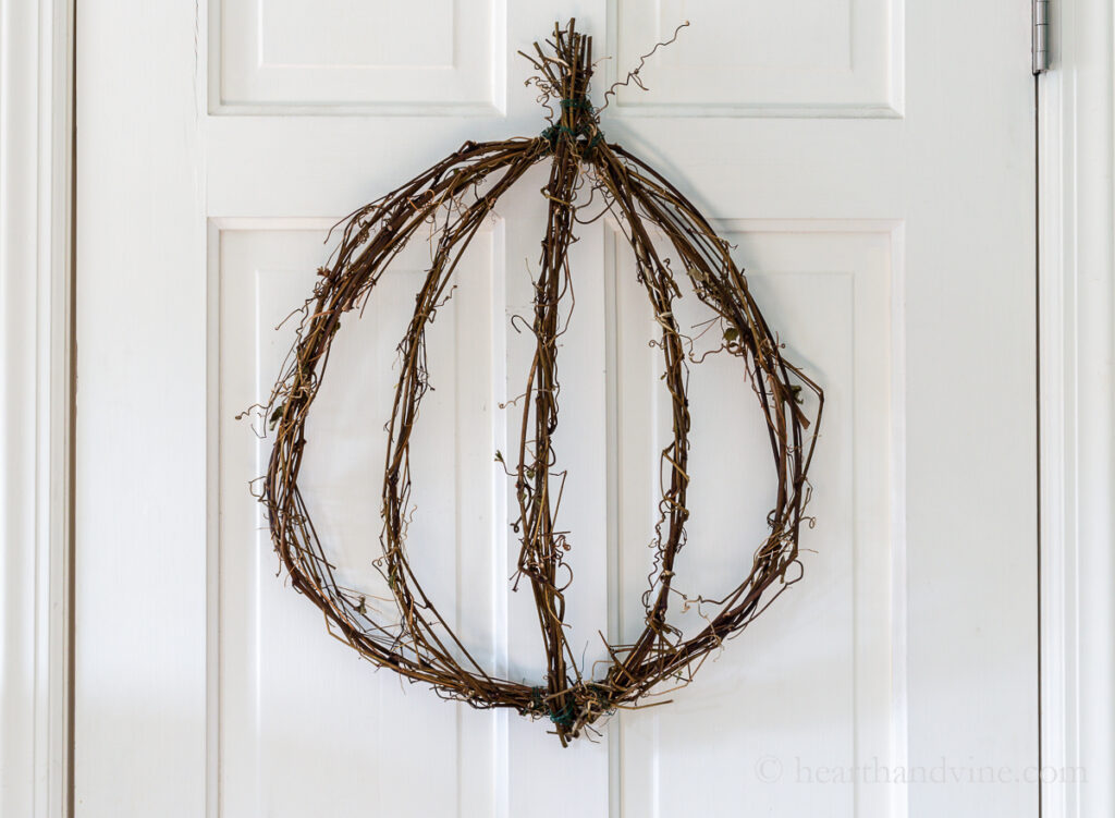 Grapevine pumpkin wreath on white door.