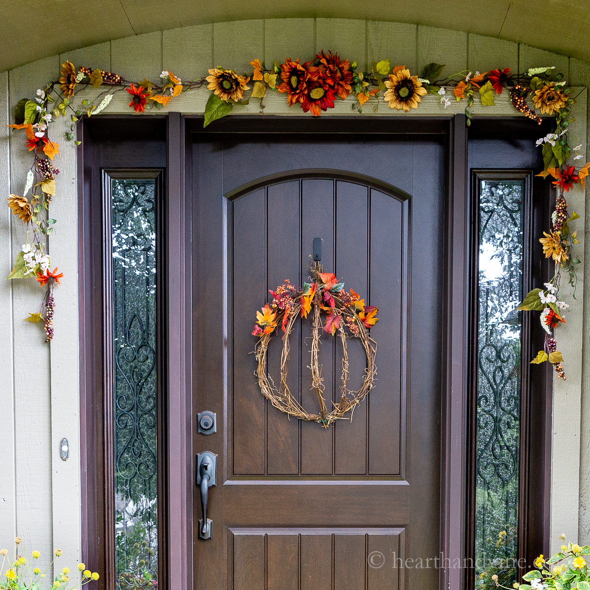 Fall decorated front door with a pumpkin wreath and fall garland