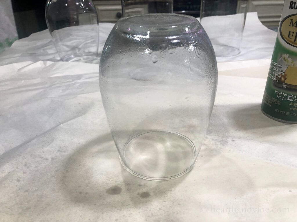 A rounded clear glass upside down with  a vinegar and water spray on top.