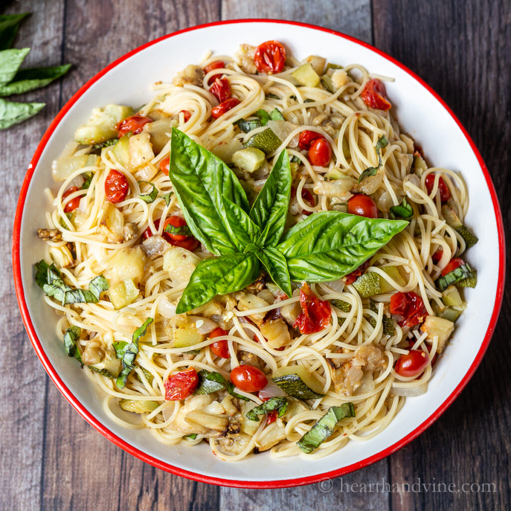 Large serving bowl of roasted ratatouille with fresh basil garnish.