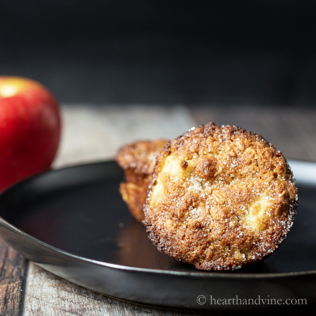 Apple cinnamon oat muffins on a plate next to an apple.
