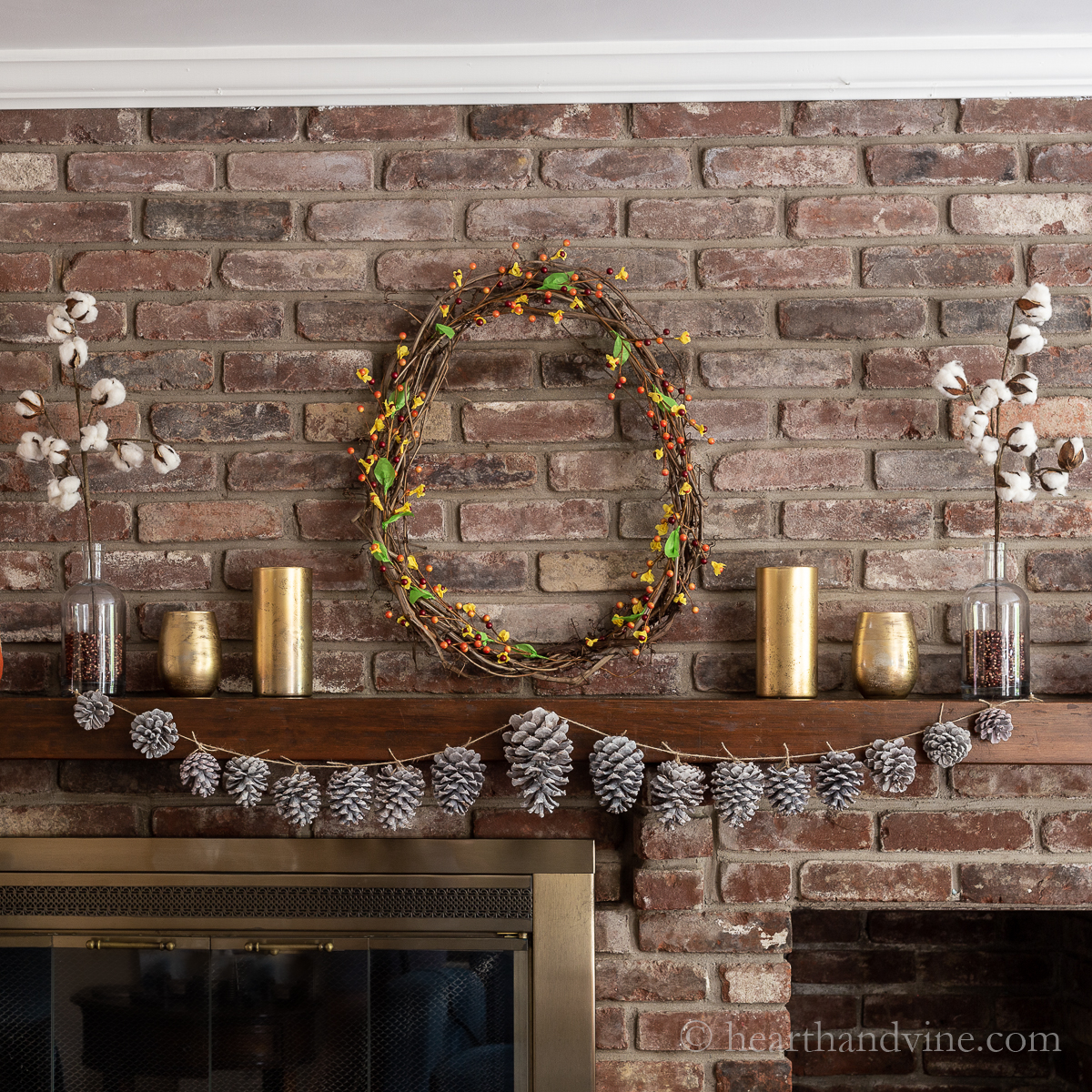 Fall mantel decorations with a wreath, pinecone garland and gold mercury candle holders.