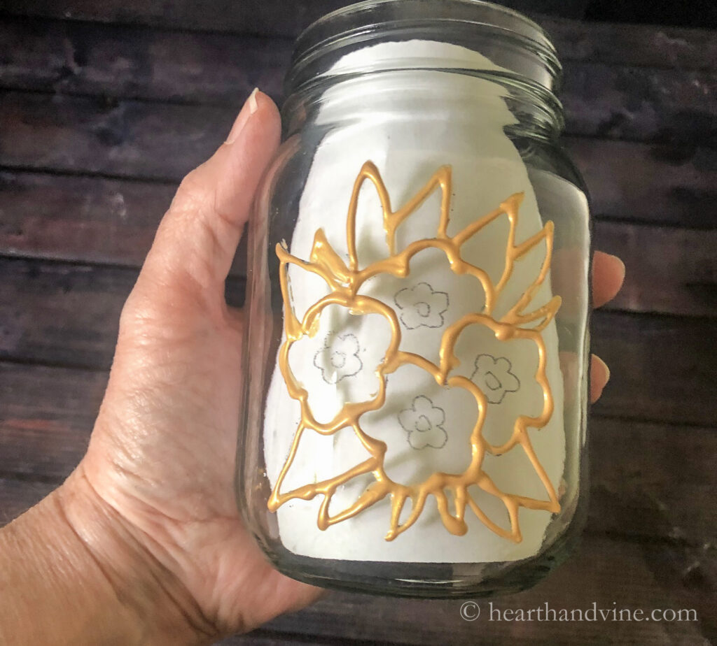 Gold outliner paint on pattern on a mason jar.