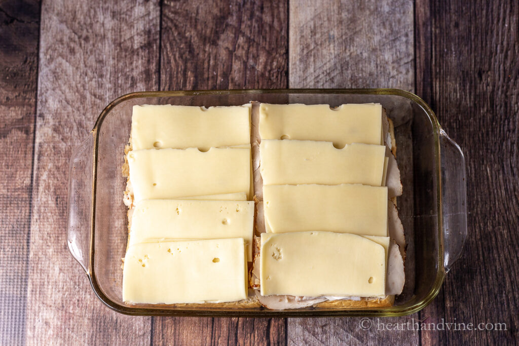 Slices of gouda cheese on top of turkey and slider buns.