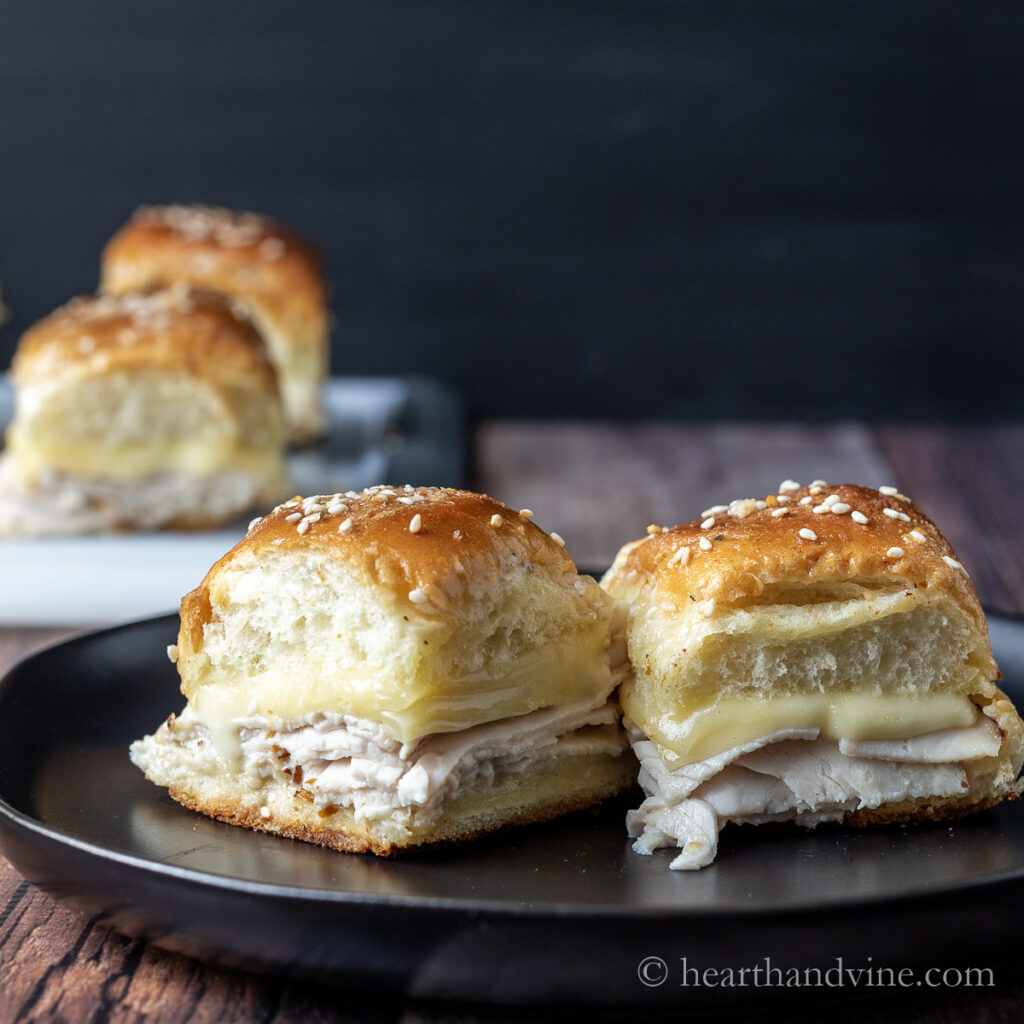 Two turkey ranch sliders with gouda cheese on a plate.