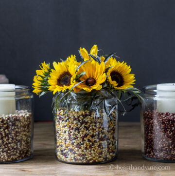 Apothecary jars with sunflowers, candles and colored popcorn kernels.