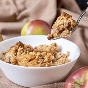 Bowl of apple crisp with a spoon taking a bite.