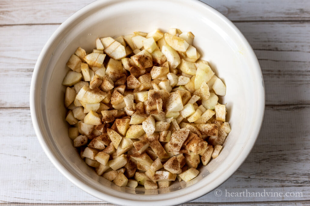 Large bowl of peeled and diced apples with cinnamon.