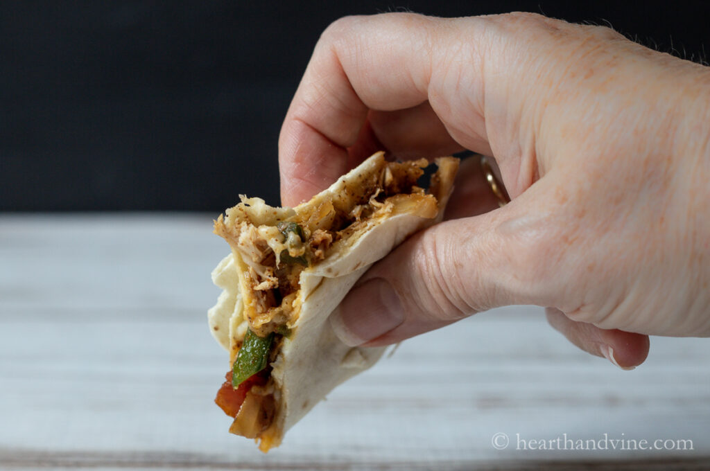 Hand holding a slice of chicken quesadilla.