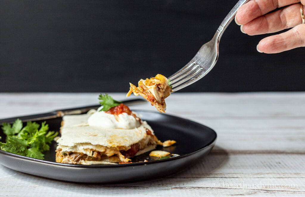 Fork taking a bit of baked sheet pan chicken quesadilla.