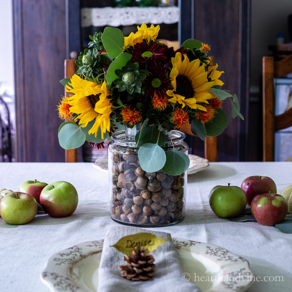 Fall tablescape ideas with fall floral centerpiece, a fruit runner and leaf place card.