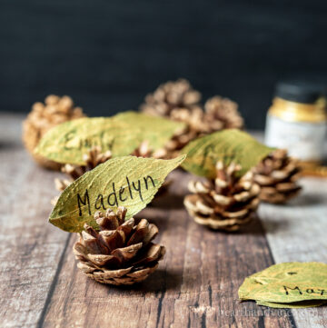 Gold real leaf place cards on pinecone holders.