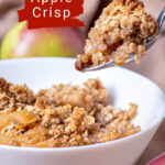 Bowl of apple crisp with oat a spoon lifting a serving.
