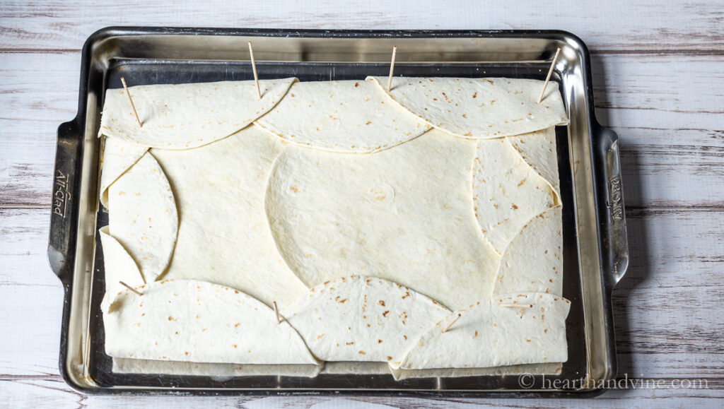 Edges of the tortillas are folded over to close the mix inside with wooden toothpicks holding them in place.