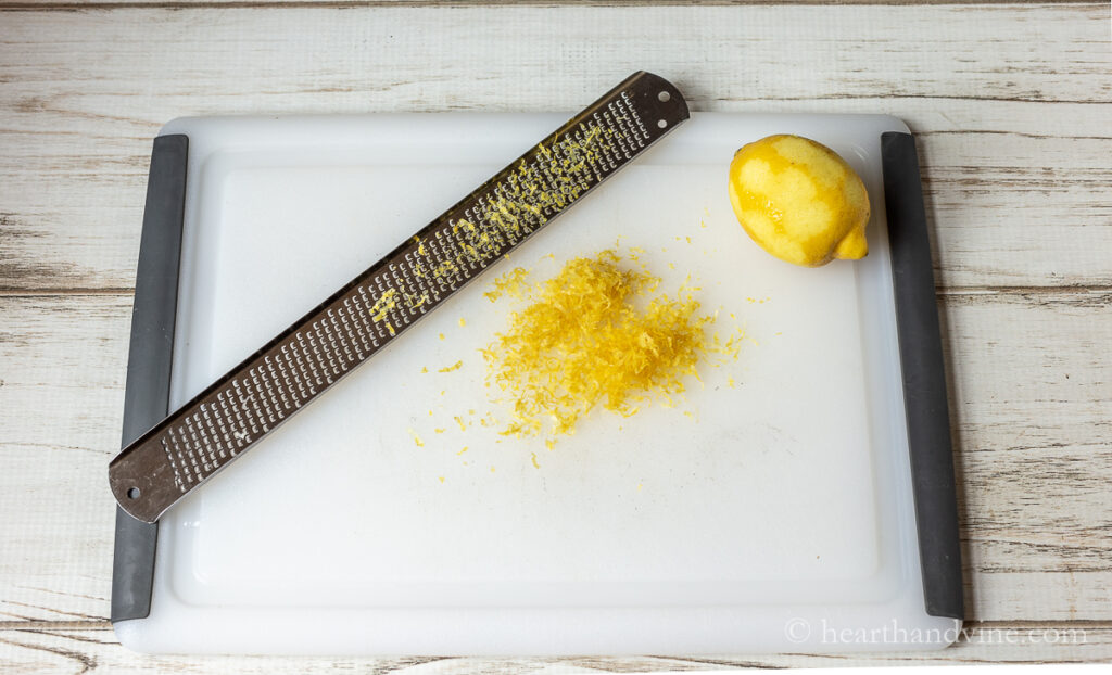 Microplane zesting lemon on a cutting board.