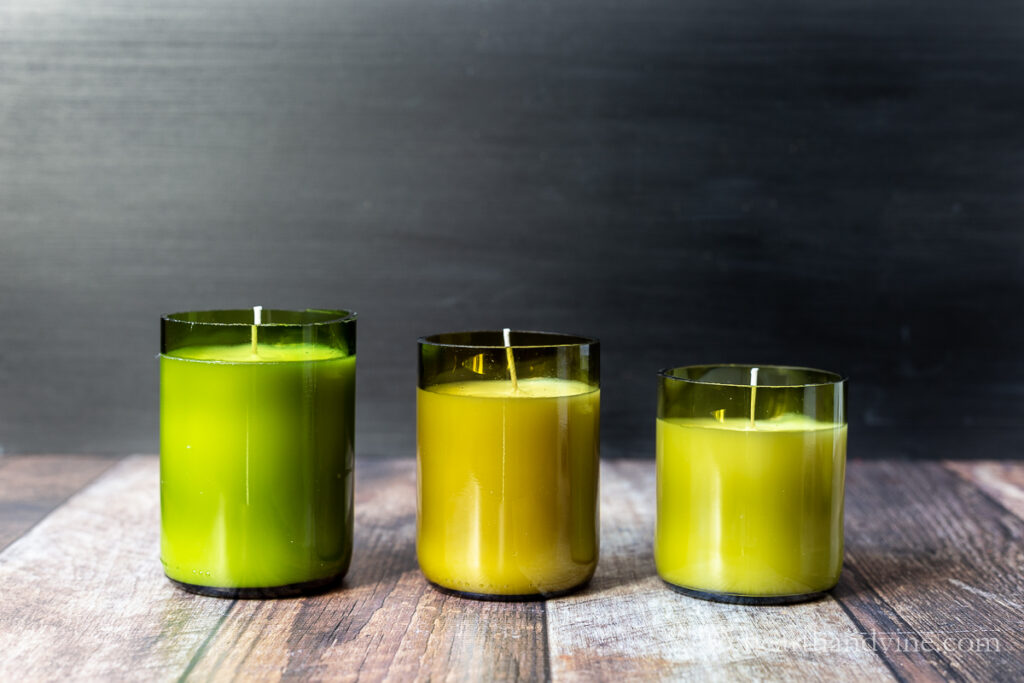 Three wine bottle candles in varying heights.