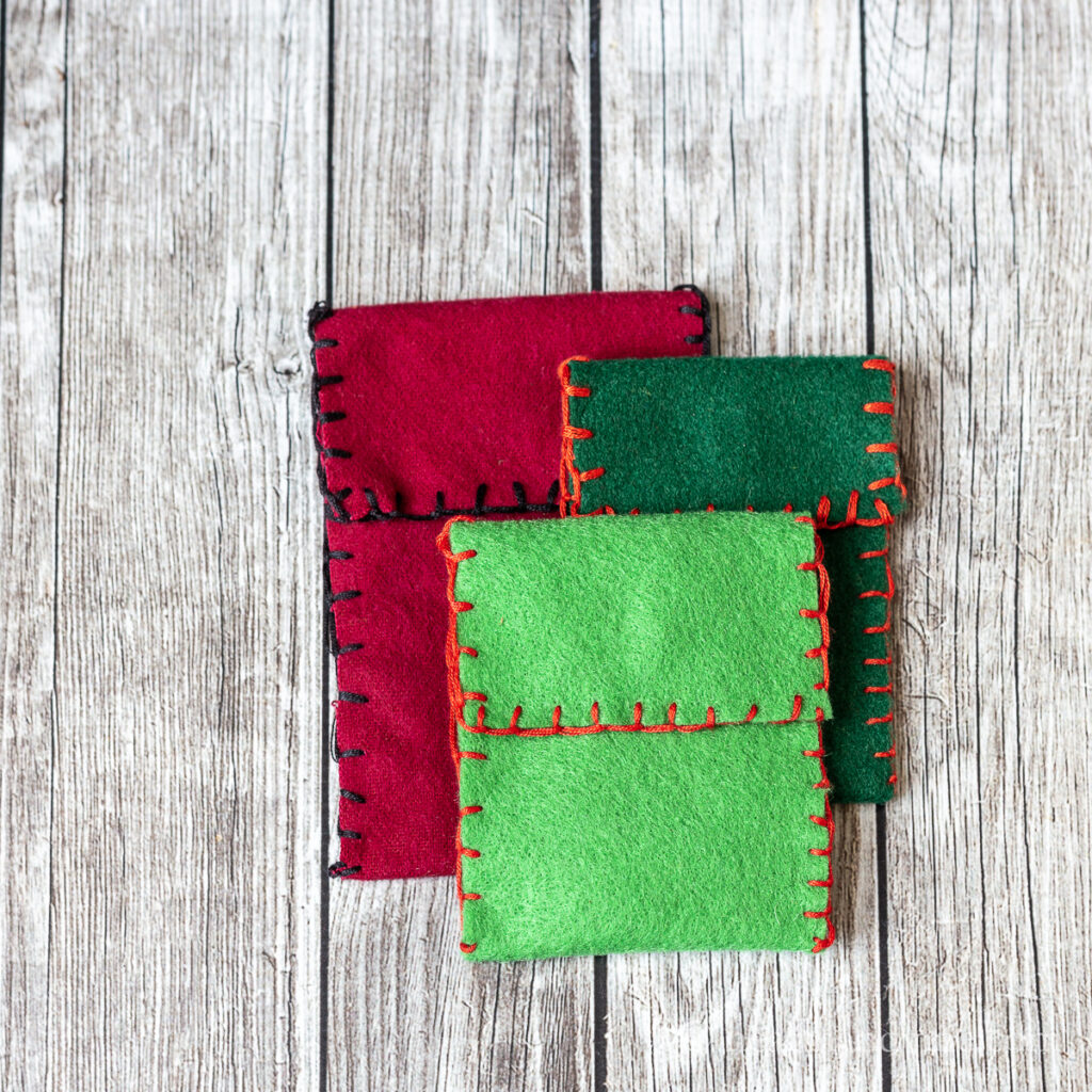 Red, dark green and light green felt bags with contrasting stitching.
