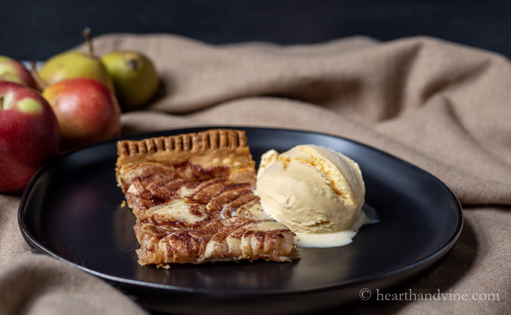 Serving of apple tart with a scoop of vanilla ice cream.