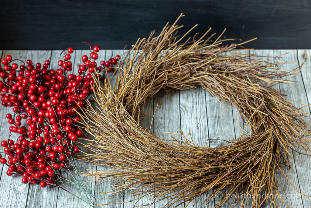 Red berry stems next to a twig wreath base.