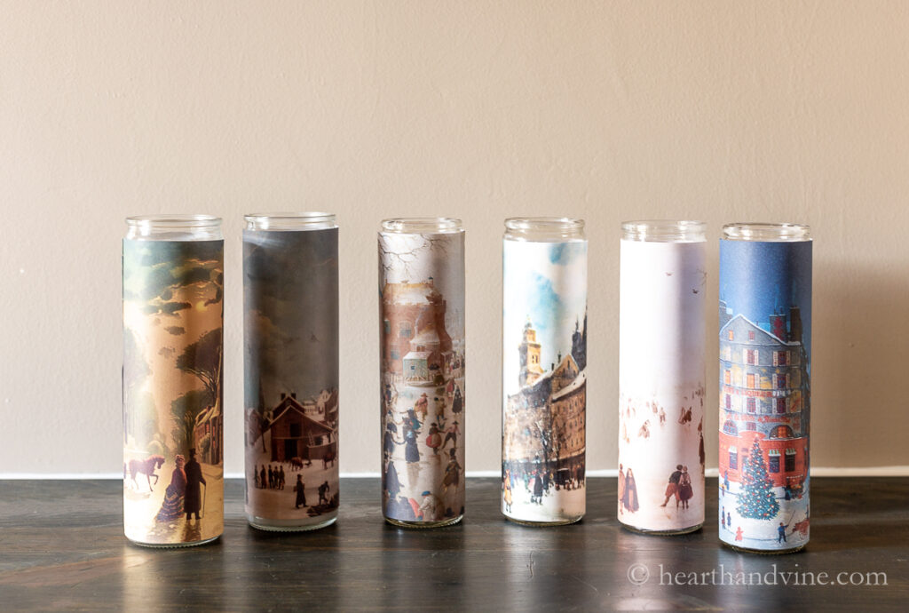 Six vintage glass candles on a chest. Christmas and winter vintage scenes cover the candles.