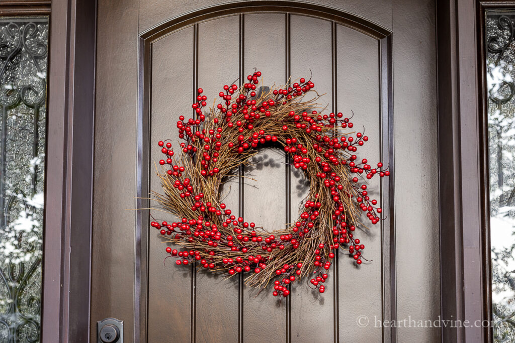 Red berry wreath on a brown front door.
