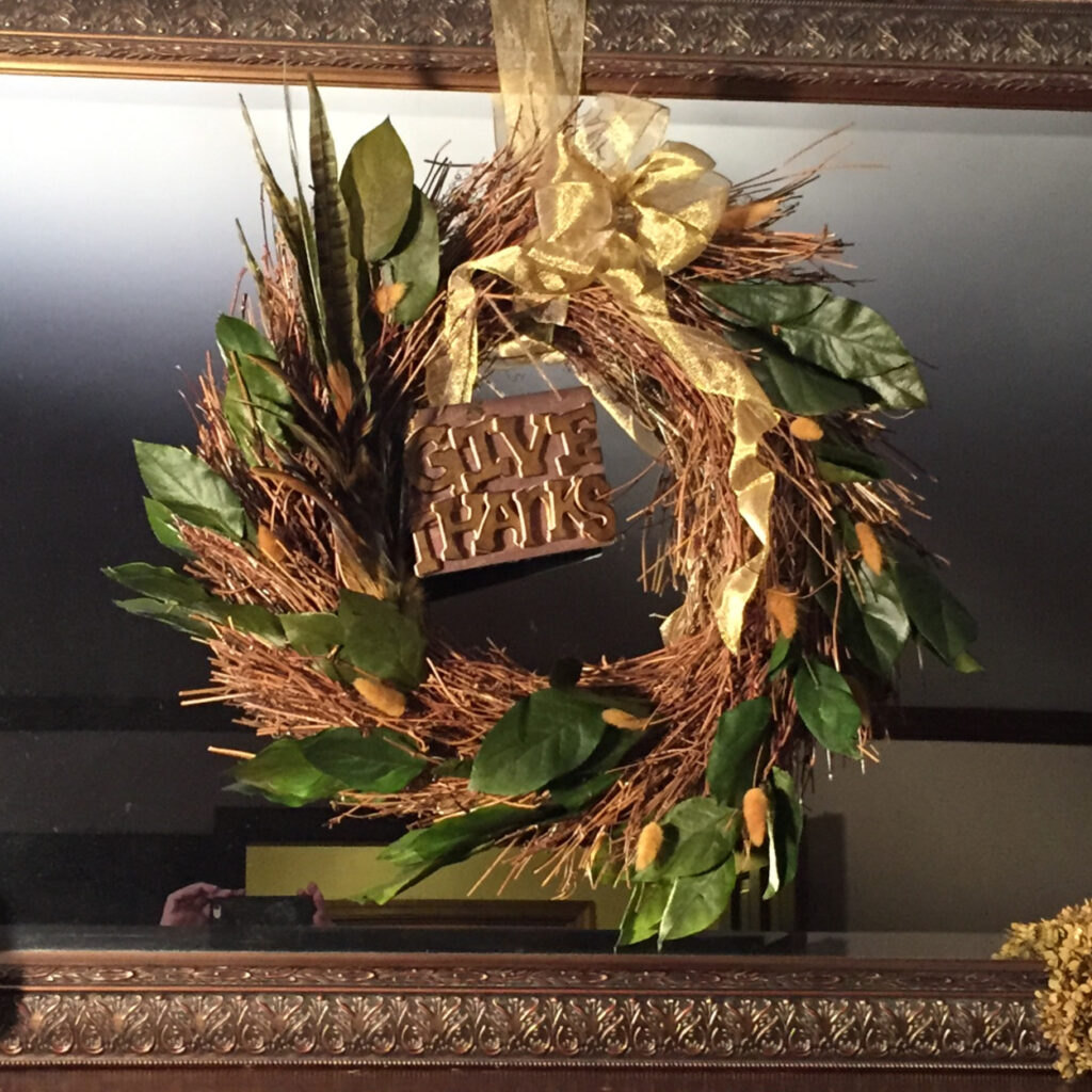 Wreath on mirror with a give thanks sign.