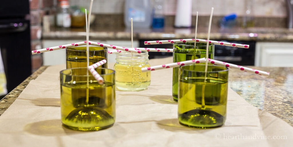 Wine bottle bottoms filled with melted soy wax. Straws holding wicks in place.
